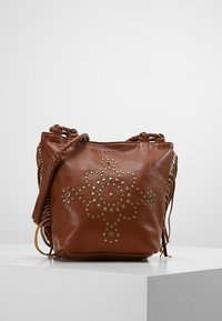 Brązowa skórzana torba typu bucket z złotymi ćwiekami w kwiatowy wzór, plecionym paskiem na ramię i frędzlami po bokach. Gładka faktura, casualowy design.