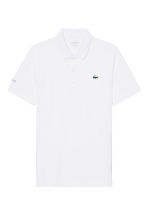 Polo bianca a maniche corte con colletto e abbottonatura a tre bottoni, con un piccolo logo di coccodrillo verde sul petto.