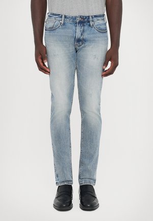 Light blue denim jeans with a straight cut, featuring subtle fading, whiskering, and five-pocket design. Worn with black shoes.