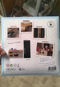 Zestaw kuchenny do domku dla lalek Lundby, z jasnobrązowym blatem, czarną lodówką oraz miniaturowymi akcesoriami kuchennymi z szczegółowymi pokrętłami.