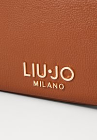 Borsa in pelle con texture animale caratterizzata da dettagli del logo "LIU·JO MILANO" in tonalità oro lucido. Superficie liscia con leggero effetto venato per una maggiore texture.