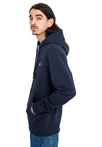 Sudadera azul marino hecha de tela suave, con un bolsillo tipo canguro, capucha ajustable con cordón y puños acanalados. Detalle de logotipo sencillo en la parte delantera.