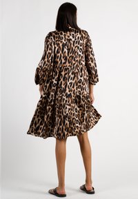 Kleid mit Leopardenmuster, gestuftem Design, Dreiviertelärmeln und fließender Passform. Hergestellt aus weichem Stoff, verfügt es über eine schwarz-beige Farbpalette.