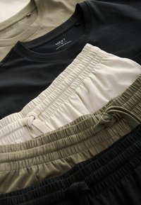 T-shirtar i svart, olivgrön och beige samt shorts med elastisk midja i svart och olivgrön. Materialen är mjuka med en slät yta och samlade detaljer.