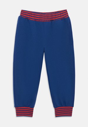Pantalon de survêtement bleu pour enfants avec taille élastique et poignets présentant des rayures horizontales rouges et bleues sur fond blanc.