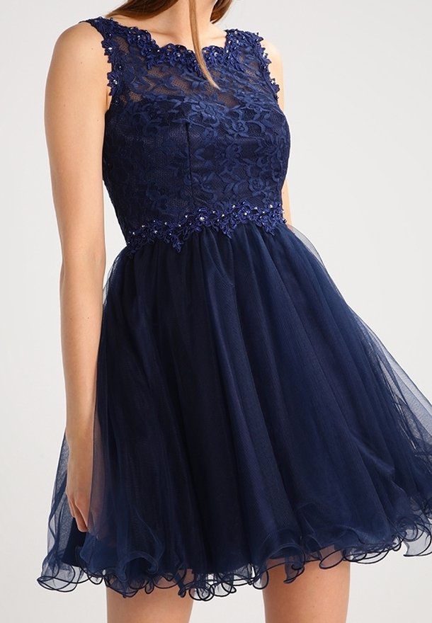 Robe bleu marine sans manches avec corsage en dentelle florale, taille perlée et jupe en tulle ample se terminant au-dessus des genoux.