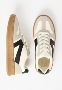 Pair of white and beige sneakers with black accents and gum rubber soles, shown from top and side views on a white background.