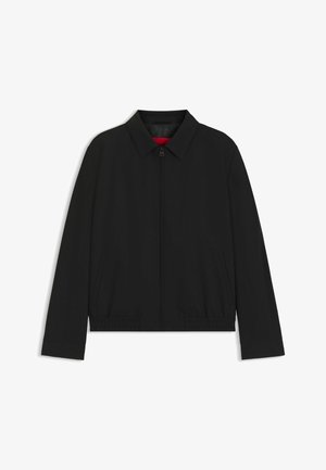 Veste zippée noire avec un col, poches latérales, taille élastique et doublure intérieure rouge. Tissu lisse et design ajusté.