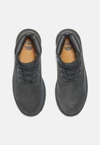 Zapatos de cuero negros con punteras redondeadas, que cuentan con plantillas texturizadas, cordones negros y un cuello acolchado para mayor comodidad.