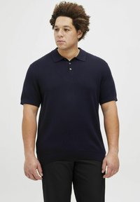 Tamsiai mėlynas trumpų rankovių polo marškinėliai su tekstūriniu raštu, trijų mygtukų apykakle ir gumas apykakle. Suderinta su tamsiomis kelnėmis.