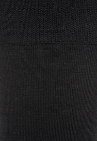 Tessuto di maglia nera con una trama liscia e un fine motivo a coste, che mostra cuciture uniformi e un colore consistente su tutta la superficie.