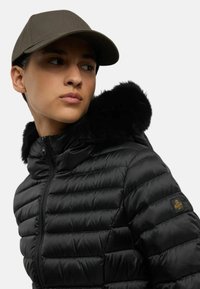 Giacca a vento nera con chiusura a zip e fascia in pelliccia sintetica nera sul cappuccio, caratterizzata da cuciture orizzontali e una piccola etichetta con logo sulla manica.