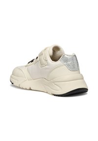 Sneaker couleur crème avec une tige texturée, une sangle réglable et un accent argenté brillant au talon ; semelle en caoutchouc avec un motif de bande de roulement noir.
