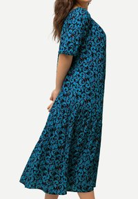 Sininen ja teal-mallinen mekko, jossa on kukkakuosi. Lyhyet hihat, polvipituinen, rento istuvuus, sileä kangas ja kerätty vyötärökohta.