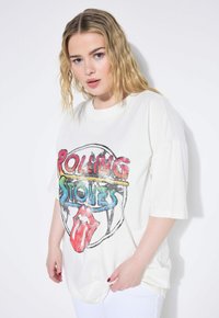 Hvid oversized T-shirt med et farverigt Rolling Stones grafik, med røde, blå og gule accenter, korte ærmer og blød stofstruktur.