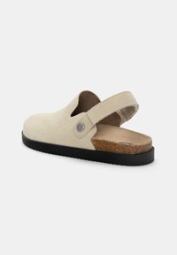 Sandal cu toc deschis din suede bej, curea ajustabilă, vârf rotund, accent din plută maro pe toc și talpă texturată din cauciuc negru.