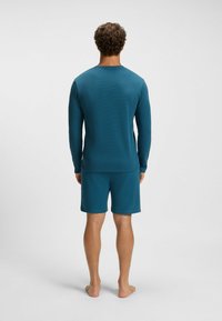 Teal long-sleeve shirt with a textured pattern and matching shorts. The fabric appears lightweight and breathable. No visible branding.