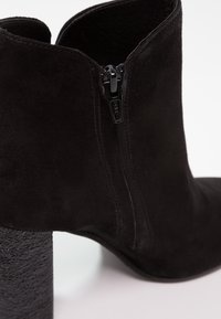 Czarne zamszowe botki za kostkę z teksturowanym słupkowym obcasem, z bocznym zamkiem błyskawicznym i gładką powierzchnią, prezentujące nowoczesny design.