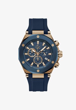 Kronografur med en blå struktureret urskive, roseguld accenter, ottekantet kasse og en blå gummirem. Funktioner inkluderer sub-ure og datovisning.