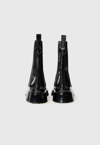 Botas de tobillo de charol negro con tacón grueso, que presentan una textura suave, detalles de costura vertical y lengüetas en la parte trasera.