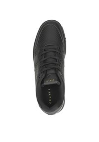 Zapatilla de cuero negro con detalles perforados, puntera redonda, cordones negros y acentos dorados en la lengüeta y el lateral. Suela de goma, diseño elegante.