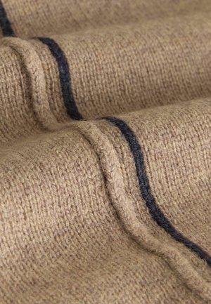 Tivora tricotată de culoare bej cu o suprafață texturată, având dungi orizontale de culoare albastru închis. Vederea de aproape subliniază țesătura și detaliile.
