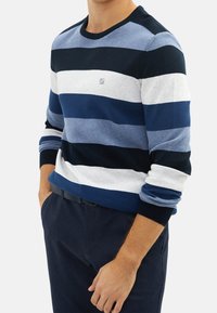 Gestreifter Pullover in Marineblau, Hellblau und Grau. Gerippter Rundhalsausschnitt und Bündchen, glatte Textur, Logodetail auf der Brust.