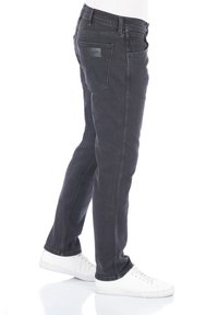 Jeans in denim grigio scuro con design a gamba dritta, dotati di etichetta sulla tasca posteriore e cuciture sottili. Abbinati a sneaker bianche.