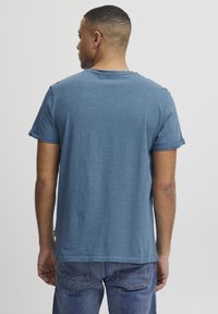 Lys blå bomull t-skjorte med rund hals og rullede korte ermer, brukt med denim jeans, viser bakvisning og glatt tekstur.