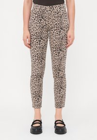 Kalhoty s leopardím vzorem v těsném střihu, vyrobené z pružného materiálu, délka ke kotníkům. Texturovaný povrch s odstíny béžové a černé.