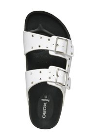 Sandalia de slide de piel blanca con dos hebillas ajustables, tachuelas decorativas plateadas y una plantilla acolchada negra. Nombre de la marca "GEOX" visible.
