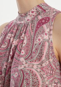 Mouwloze blouse in een roze paisleypatroon, met een hoge halslijn, geplooid ontwerp en een lichte, gladde stofstructuur.