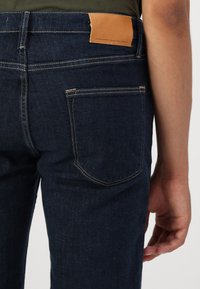 Σκούρες μπλε τζιν παντελόνες από τζιν με δερμάτινη ετικέτα στην πίσω μέση, που διαθέτουν εφαρμοστό σχέδιο και �παραδοσιακές πίσω τσέπες.