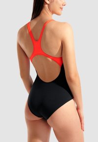 Svart baddräkt med en röd racerback-design. Har en öppen rygg och en slät textur som framhäver en figurnära silhuett.