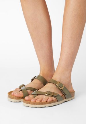 Olivgrüne Sandalen mit Korkfußbett, verstellbaren Riemen, goldenen Schnallen und strukturierter Laufsohle. Offenes Design für Atmungsaktivität.