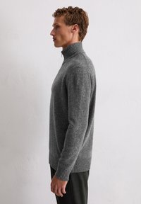 Szary, teksturowany sweter z wysokim, prążkowanym kołnierzem i długimi rękawami, charakteryzujący się dopasowanym krojem i kontrastowym prążkowaniem na dolnej części.