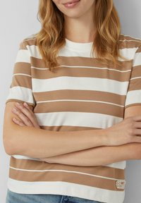 Korte mouwen, ronde hals t-shirt met horizontale bruine en witte strepen. Katoenen materiaal, met een "Good Vibes" logo op de zoom.