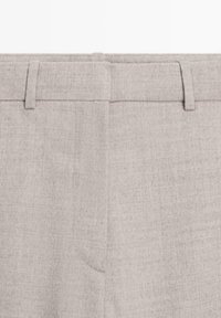 Lichtgrijze linnen broek met een flat front ontwerp, zichtbare riemlussen en geen zakken. De stof heeft een gestructureerde, lichtgekreukte uitstraling.