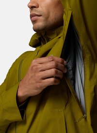 Man wearing olive green jacket unzips a side ventilation zip, revealing a patterned inner lining.