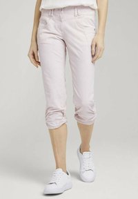 Jasnoróżowe spodenki capri wykonane z denimu, charakteryzujące się dopasowanym fasonem, przednimi kieszeniami i marszczonymi mankietami, połączone z białymi trampkami.