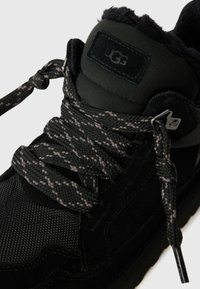 Zwarte UGG sneakers van gestructureerde stof en suede, met een gewatteerde kraag, gemêleerde zwart en grijze veters en metalen ogen.