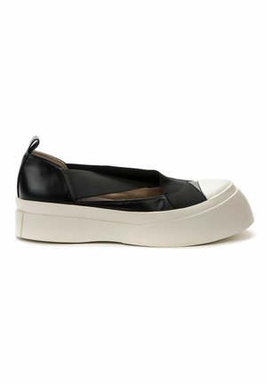 Chaussure noire à enfiler avec semelle blanche épaisse et embout arrondi blanc, brides élastiques croisées et languette au talon.