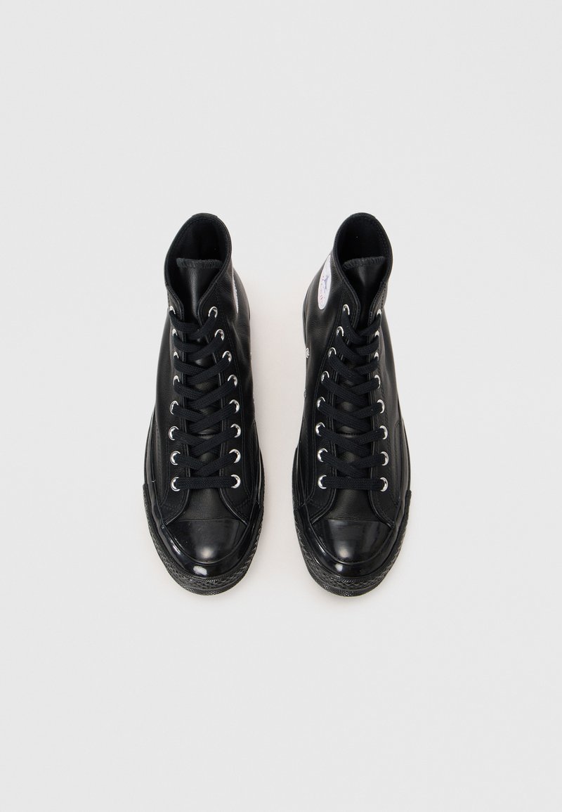Schwarze High-Top-Sneaker aus Leder mit silbernen Ösen, flachen Schnürsenkeln, Gummisohle und einem kleinen Logopatch an der Außenseite.
