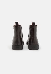 Schwarze Lederknöchelboots mit strukturiertem Finish, Reißverschluss auf der Rückseite, rotem Akzent oben und Gummisohlen mit Markenlogo.