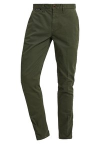 Olivengrüne Baumwoll-Chinos mit geradem Schnitt, Knopfverschluss und Gürtelschlaufen; glatte Textur und dezente Markenlogos am Bündchen.