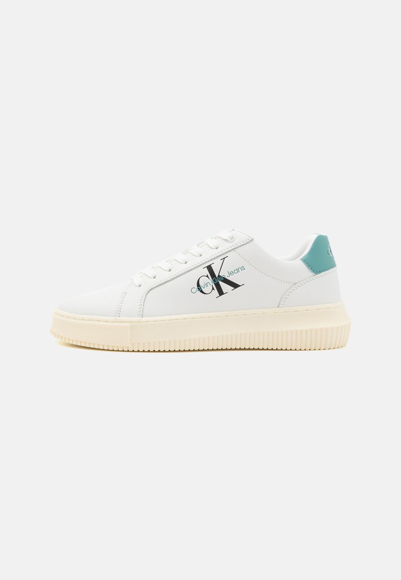 Witte leren sneakers met een gestructureerde off-white zool, teal hielaccent en zwart logo aan de zijkant. Glad oppervlak en vetersluiting.
