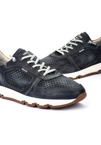 Chaussures en cuir navy avec un design perforé, lacets gris et semelle sportive de couleur claire. Présente un logo et des accents orange contrastants.