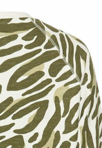 Bomulds skjorte med et grønt og beige dyreprint. Designet inkluderer uregelmæssige striber med en blød tekstur og synlige syede sømme.