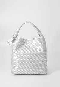 Πλεκτή ασημένια τσάντα με στρογγυλό σχήμα, υφασμάτινη επιφάνεια και κοντό χερούλι. Διαθέτει μια λευκή ετικέτα με το λογότυπο.