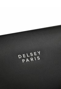Matériau noir texturé arborant le nom de la marque "DELRSEY PARIS" en broderie blanche, centré sur la surface.
